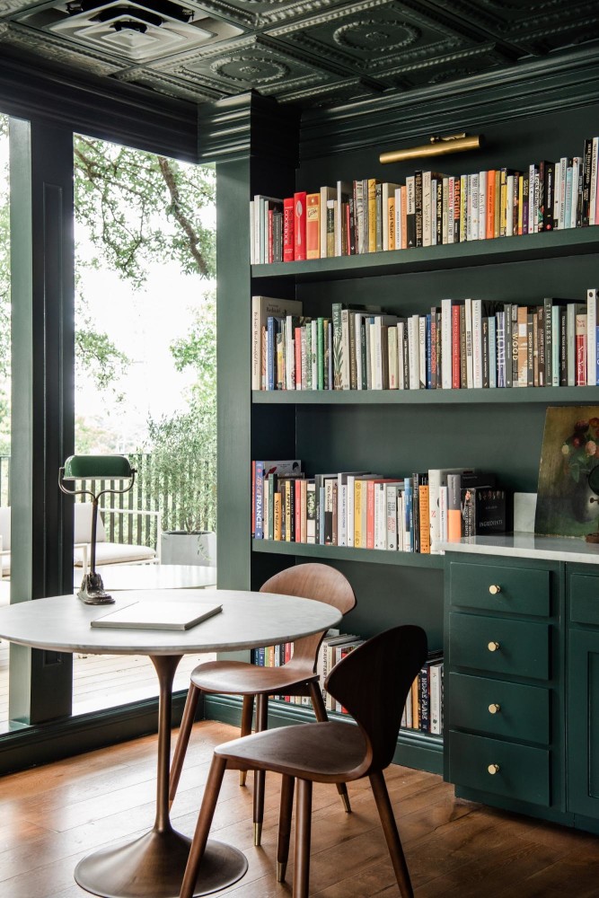 Bespoke green library with round table and mid-century like chairs 