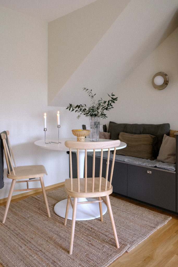 IKEA breakfast corner with round table, chairs, bench and rug under sloped ceiling